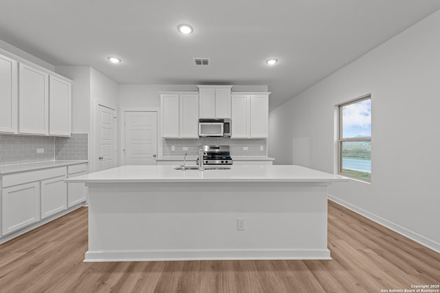 kitchen featuring a sink, appliances with stainless steel finishes, decorative backsplash, and light countertops