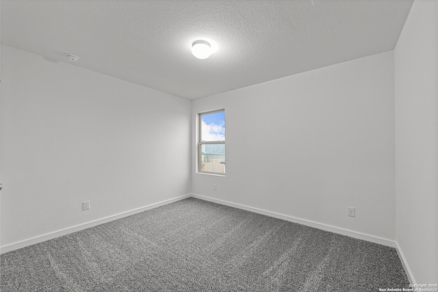 unfurnished room with a textured ceiling, dark colored carpet, and baseboards