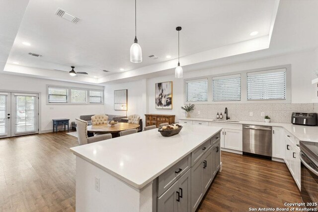 kitchen with open floor plan, stainless steel appliances, light countertops, visible vents, and a raised ceiling