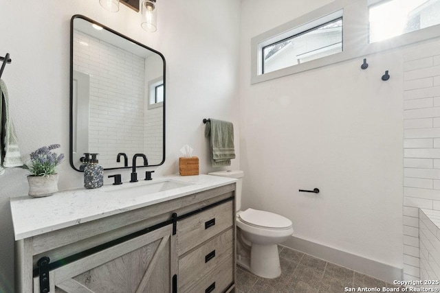 full bath featuring baseboards, vanity, and toilet