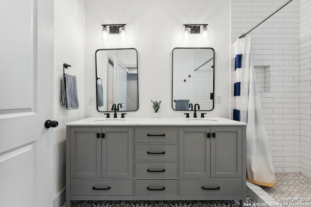bathroom with double vanity, tiled shower, and a sink