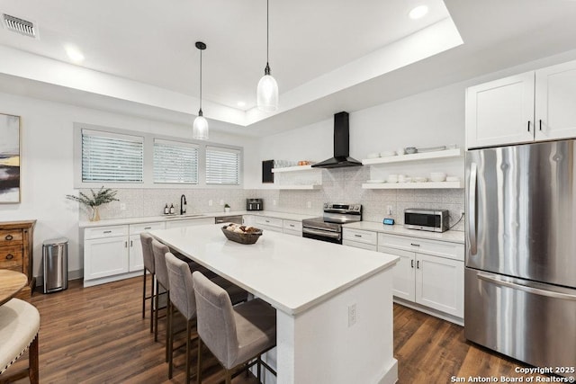 kitchen with stainless steel appliances, open shelves, wall chimney range hood, visible vents, and a sink