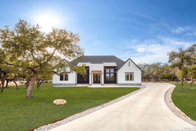 modern farmhouse style home with french doors, driveway, a front yard, and stucco siding