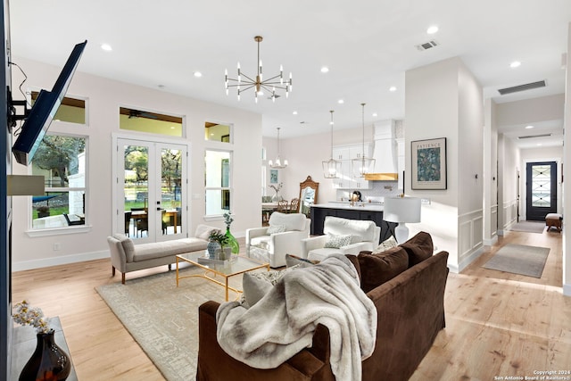 living area featuring light wood-style flooring, visible vents, recessed lighting, and a chandelier