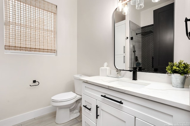 bathroom featuring toilet, baseboards, wood finished floors, a shower stall, and vanity