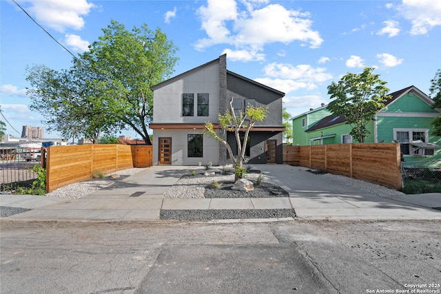 modern home with a fenced front yard and concrete driveway