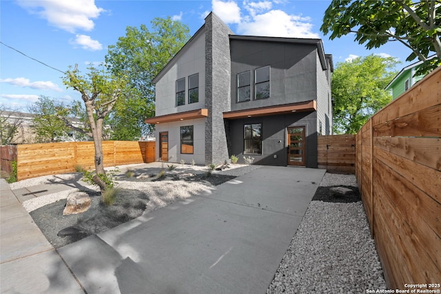 back of property with fence private yard, a gate, and stucco siding