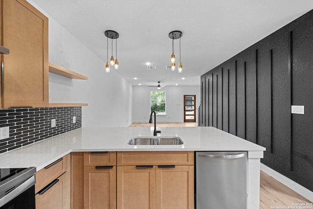 kitchen featuring light wood finished floors, stainless steel appliances, light countertops, a sink, and a peninsula