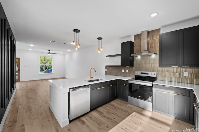 kitchen with light countertops, wall chimney range hood, stainless steel appliances, and a sink