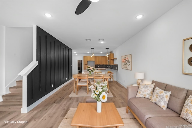living room featuring recessed lighting, light wood-type flooring, and stairway
