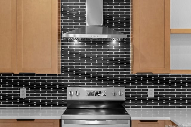 kitchen featuring light countertops, tasteful backsplash, electric stove, and wall chimney range hood