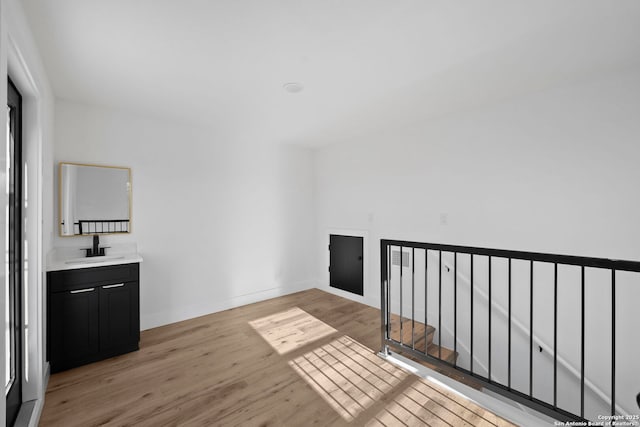 interior space featuring light wood-style flooring, baseboards, and a sink