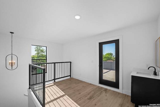 interior space with light wood-style flooring, baseboards, a sink, and a notable chandelier