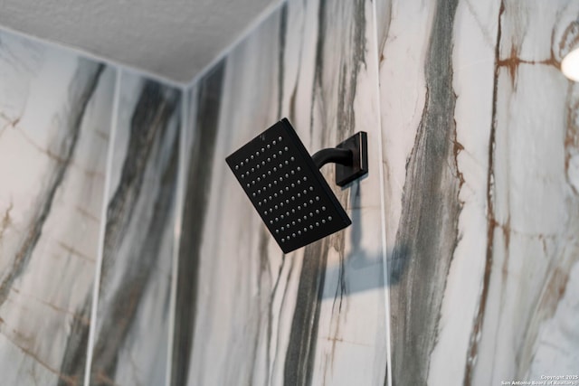 room details with a marble finish shower and a textured ceiling
