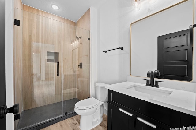 full bath with a stall shower, wood finished floors, vanity, and toilet