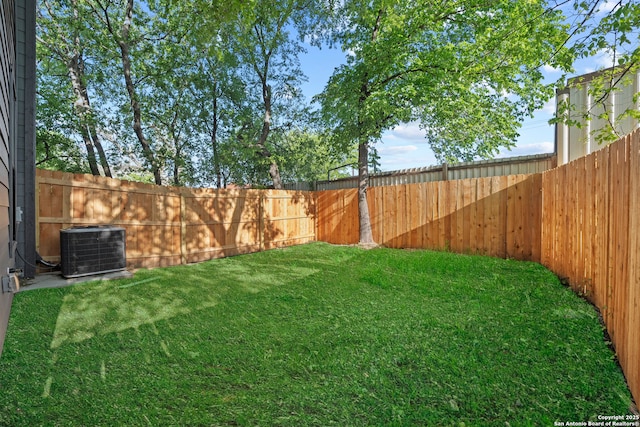 view of yard with a fenced backyard and central AC unit