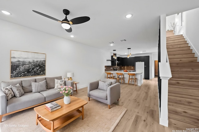 living area with recessed lighting, stairway, ceiling fan, and light wood-style flooring
