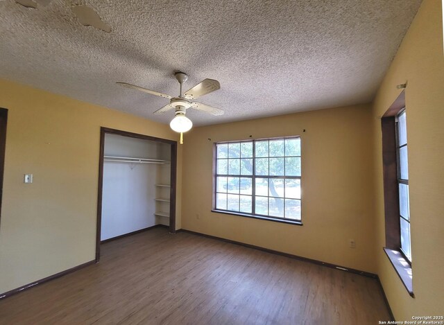 unfurnished bedroom with a textured ceiling, a closet, wood finished floors, and baseboards