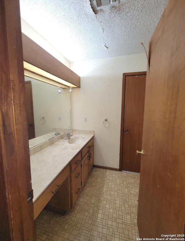bathroom with tile patterned floors, baseboards, vanity, and a textured ceiling