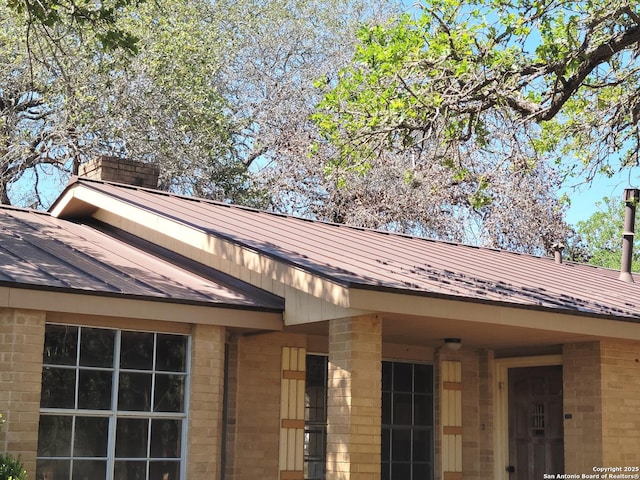 exterior details featuring metal roof and brick siding