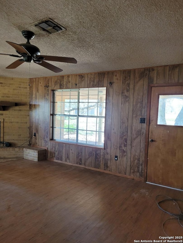 entryway featuring a textured ceiling, wood finished floors, visible vents, and wood walls