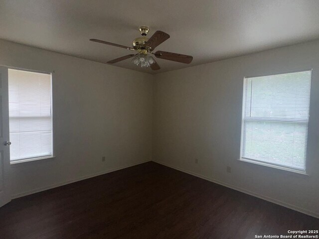 823 Dallas, Pleasanton, TX 78064 - spare room featuring a ceiling fan, baseboards, dark wood-style flooring, and plenty of natural light