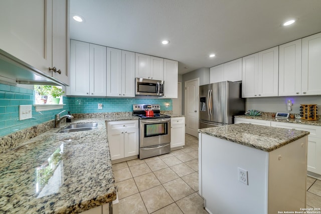 kitchen with white cabinets, a center island, stainless steel appliances, and a sink