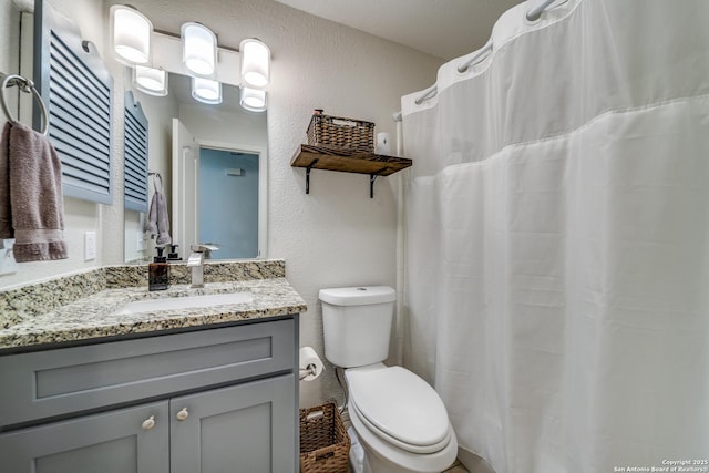 full bathroom featuring a textured wall, vanity, and toilet