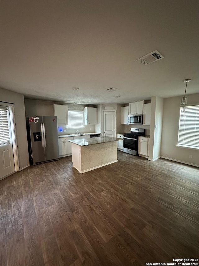 kitchen with stainless steel appliances, visible vents, a kitchen island, and dark wood-style flooring