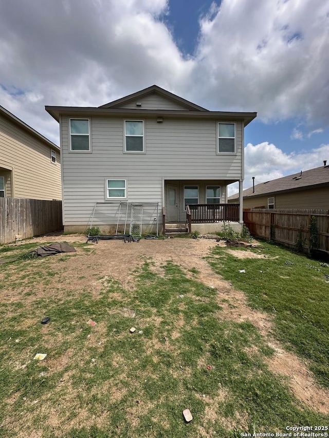 rear view of house with a fenced backyard and a lawn