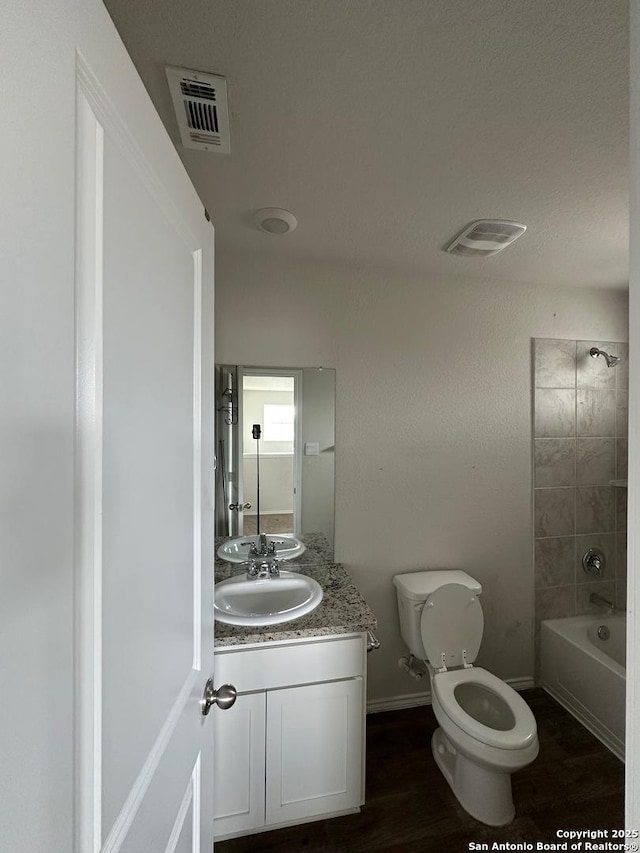 bathroom with visible vents, vanity, washtub / shower combination, and toilet