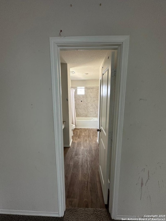 hallway with baseboards and wood finished floors