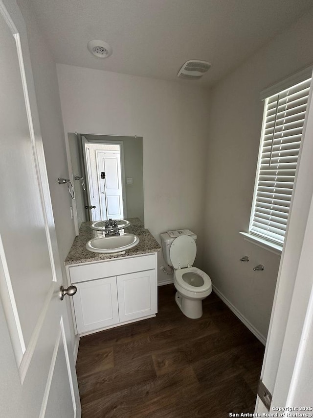 bathroom featuring wood finished floors, visible vents, toilet, and vanity