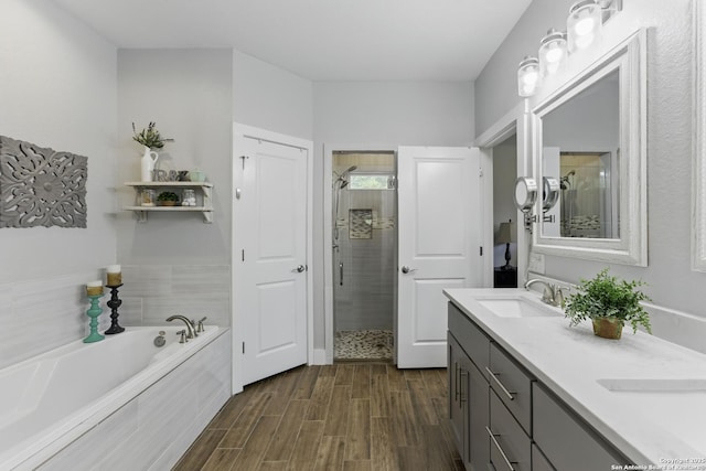 full bathroom with a bath, a shower stall, wood finished floors, and a sink