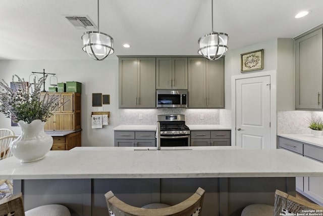 kitchen with visible vents, recessed lighting, gray cabinetry, appliances with stainless steel finishes, and a breakfast bar area