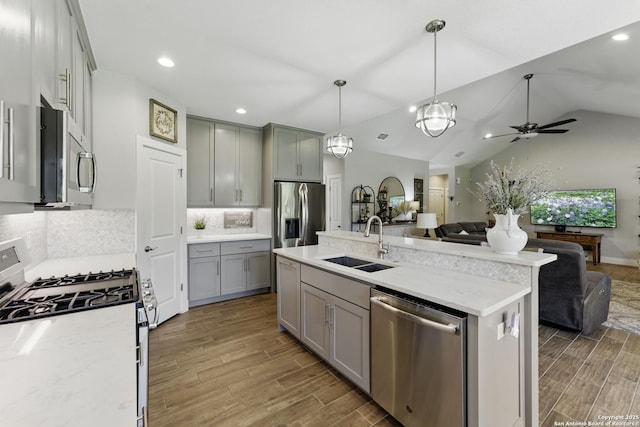 kitchen with open floor plan, appliances with stainless steel finishes, wood finished floors, and a sink