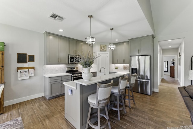 kitchen with tasteful backsplash, gray cabinets, stainless steel appliances, light countertops, and visible vents