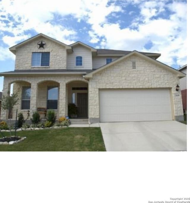 traditional-style home featuring an attached garage, driveway, covered porch, stone siding, and a front yard