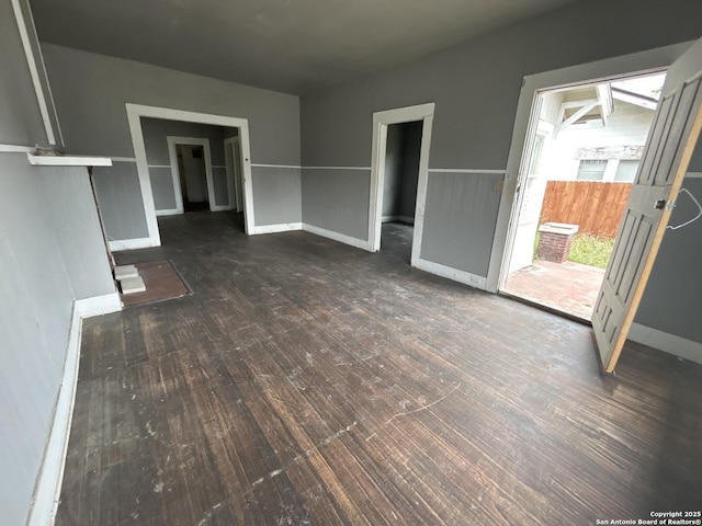 unfurnished living room featuring baseboards and wood finished floors
