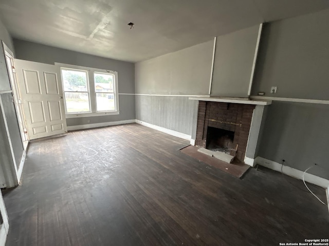 unfurnished living room featuring baseboards, wood finished floors, and a fireplace