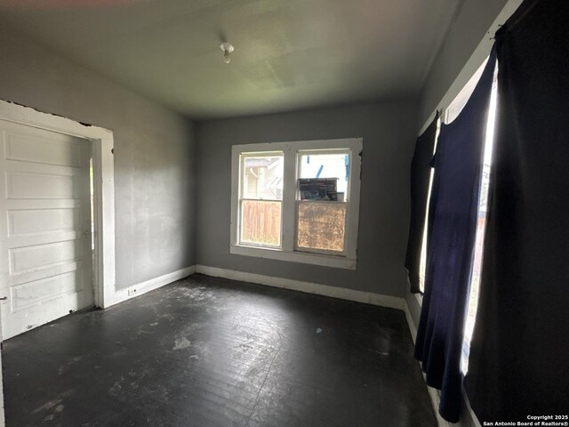 unfurnished bedroom with concrete flooring and baseboards