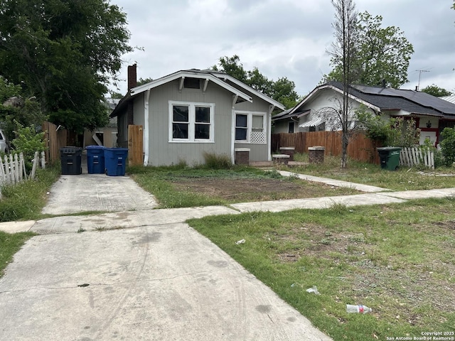 bungalow-style home with fence, a chimney, central AC, and concrete driveway