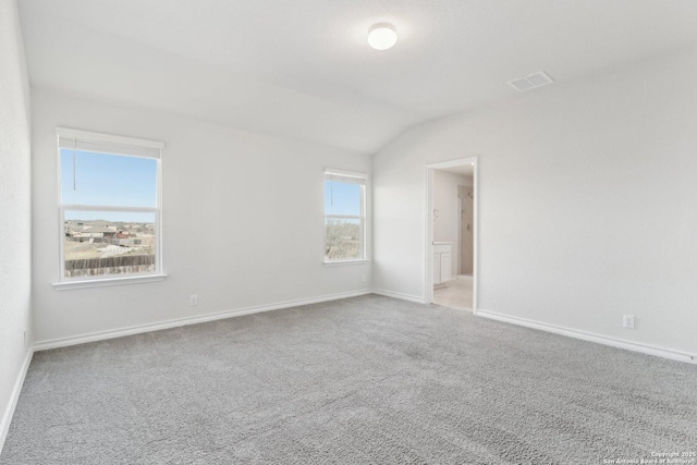 spare room with baseboards, lofted ceiling, carpet flooring, and visible vents