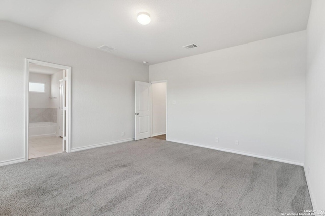 unfurnished bedroom featuring visible vents, baseboards, ensuite bathroom, and carpet flooring