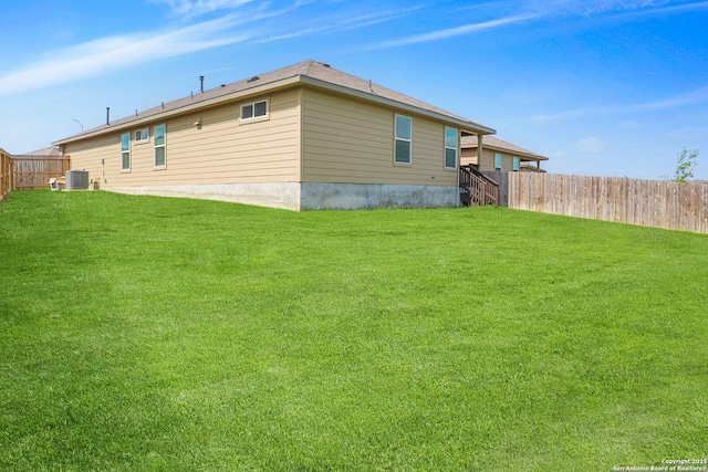 rear view of house with a lawn, a fenced backyard, and central AC