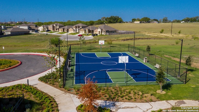 view of basketball court featuring a residential view, community basketball court, fence, and a lawn
