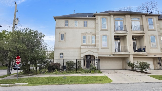 multi unit property featuring driveway, french doors, fence, a balcony, and an attached garage