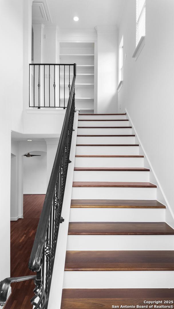 stairs with crown molding, recessed lighting, and wood finished floors