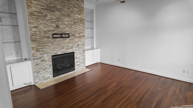 unfurnished living room with ornamental molding, built in features, wood finished floors, a fireplace, and baseboards