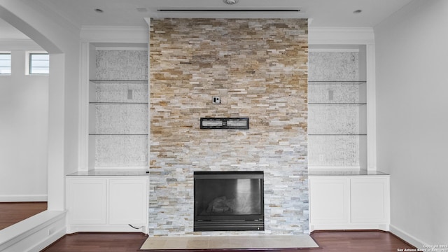room details featuring arched walkways, a glass covered fireplace, ornamental molding, and wood finished floors